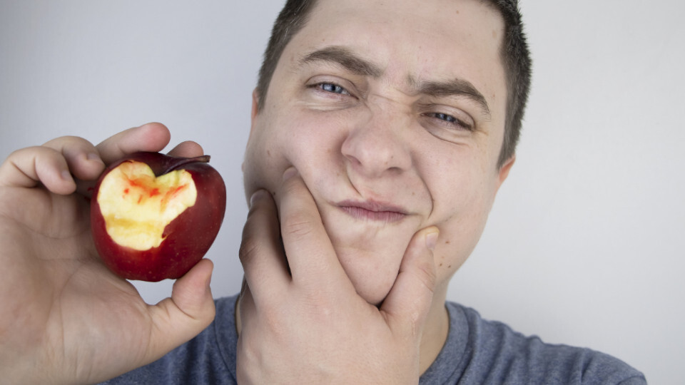 Ein Mann hält einen angebissenen Apfel mit Blutspuren in der Hand
