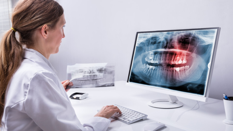 Eine Zahnärztin sieht sich eine Röntgenaufnahme auf dem Bildschirm an